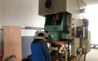 Workers work on punching machine for TV bracket