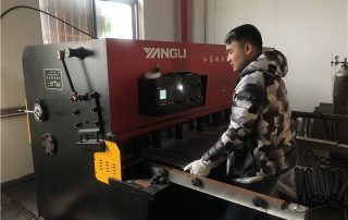 Workers work on shearing machine for TV bracket